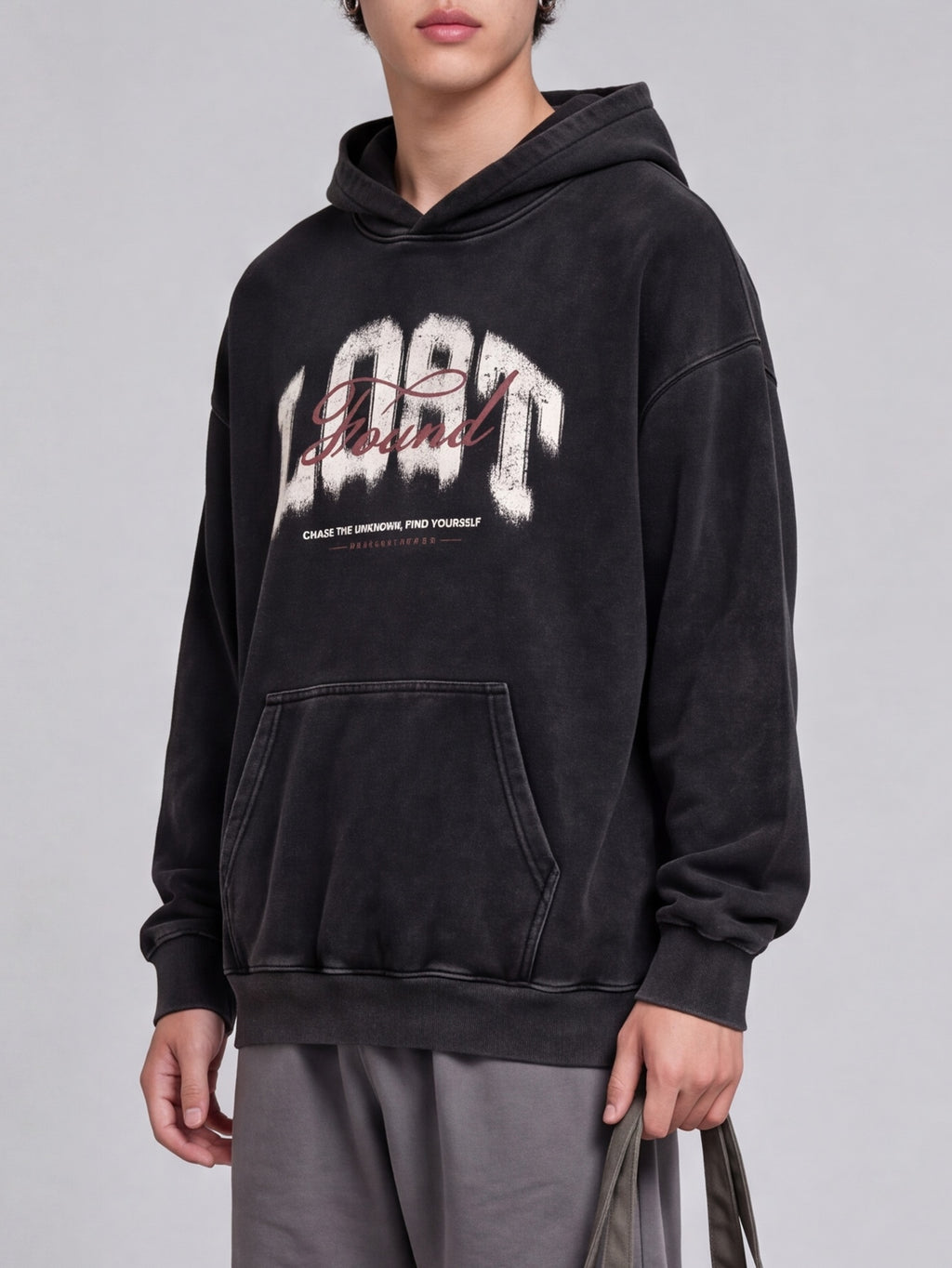 Three-quarter view of a black Lost & Found washed hoodie, showing dropped shoulders and ribbed cuffs.