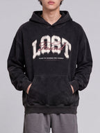Black Lost & Found washed hoodie shown from the front with hands in the kangaroo pocket.