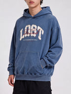 Three-quarter view of a blue Lost & Found washed hoodie with a hand in the kangaroo pocket.