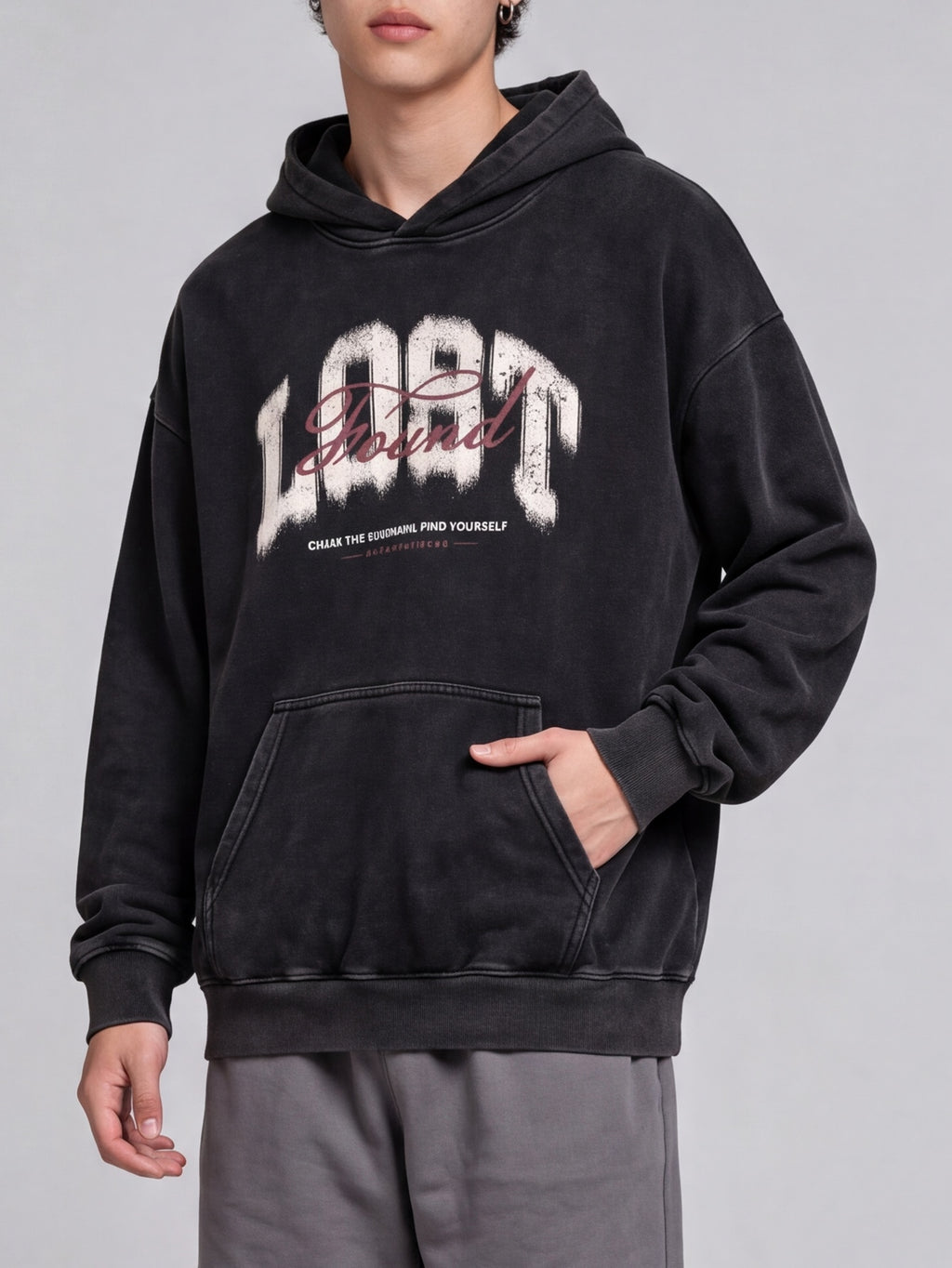 Angled view of a black Lost & Found washed hoodie with a hand in the front pocket.