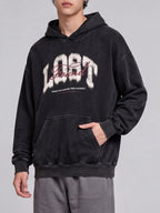 Angled view of a black Lost & Found washed hoodie with a hand in the front pocket.