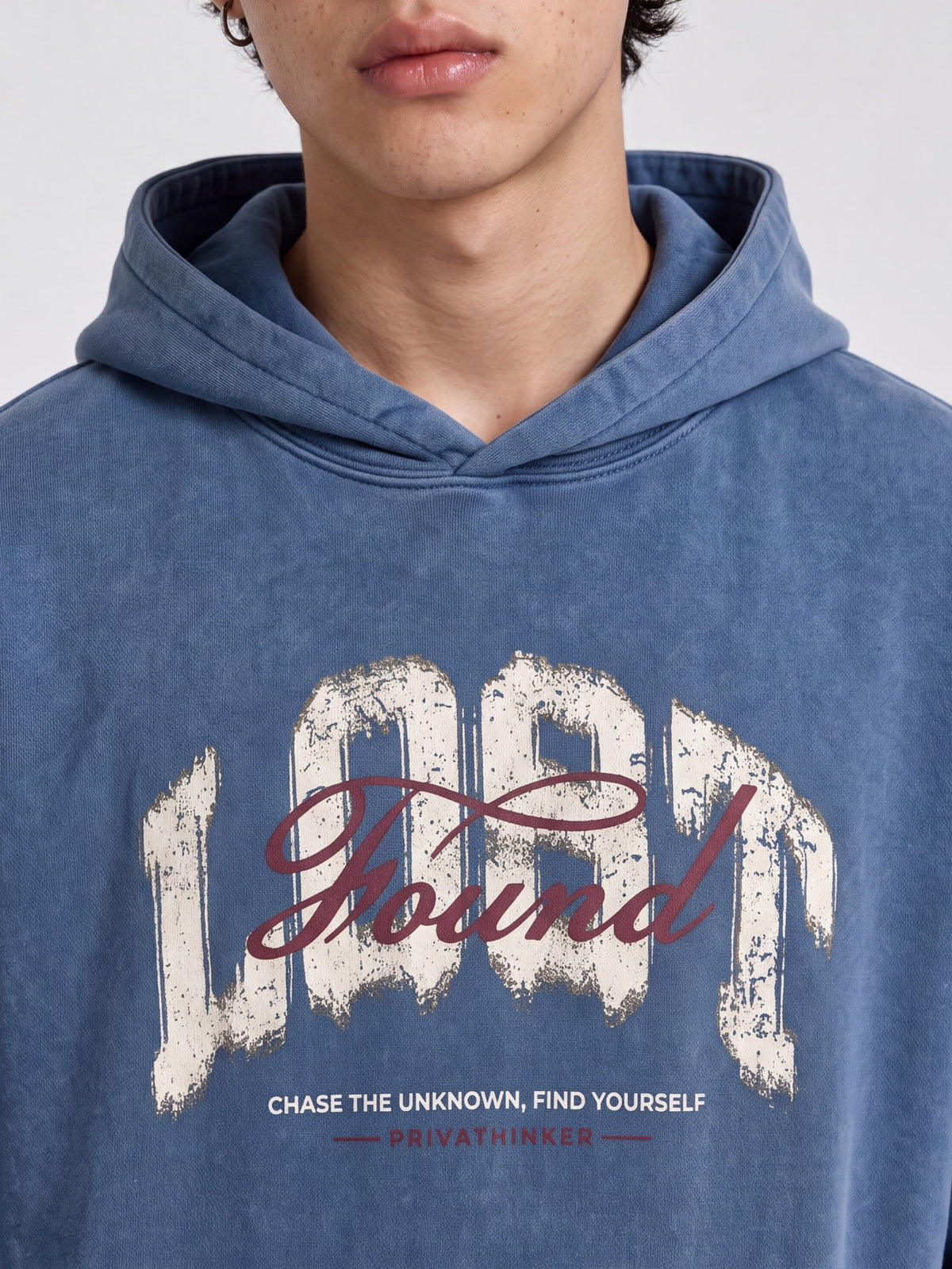 Close-up of the hood and distressed Lost & Found chest graphic on a blue washed hoodie.